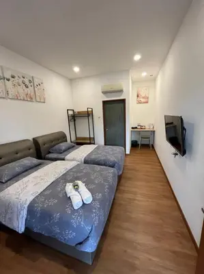 a room with two beds and a television at Raintown Cottage in Taiping
