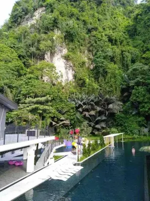 a bridge over a pool of water with a mountain at Ipoh Tambun Cove Luxe Premium Suites in Ipoh