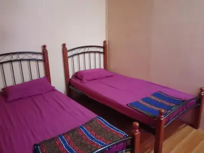 two beds in a room with purple sheets at Sobey Laris Homestay CHIKU1 in Gua Musang