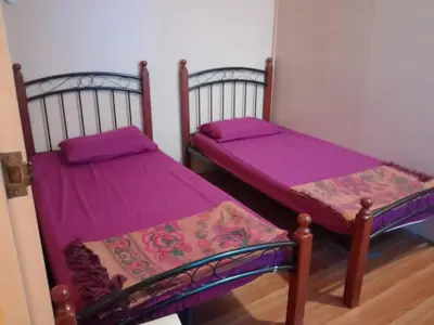 two beds in a room with purple sheets at Sobey Laris Homestay CHIKU1 in Gua Musang