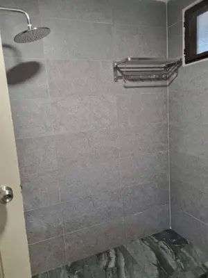 a bathroom with a shower with a tiled wall at Copthorn Homestay in Brinchang