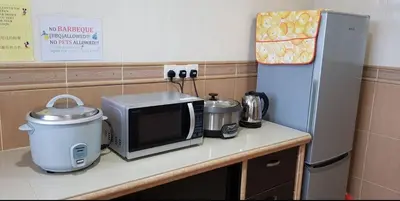 a kitchen counter with a microwave and a refrigerator at Crown Imperial Court Apartment (Madam Ng)1 in Cameron Highlands