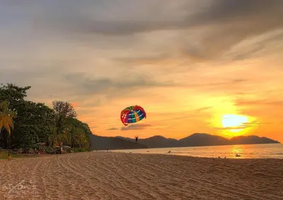 a person flying a kite on the beach at sunset at Happy Home 10 Sri Sayang Batu Ferringhi in Batu Ferringhi