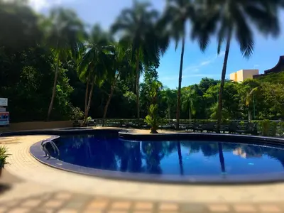 a swimming pool with palm trees in a resort at Happy Home 10 Sri Sayang Batu Ferringhi in Batu Ferringhi
