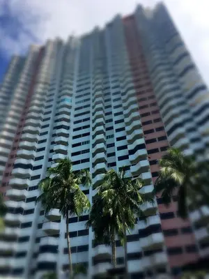 a tall building with palm trees in front of it at Happy Home 10 Sri Sayang Batu Ferringhi in Batu Ferringhi