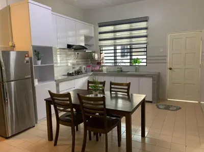 a kitchen with a table and chairs and a refrigerator at Homestay Maryam in Lumut