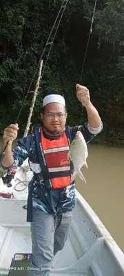 a man holding a fish on a boat at Royal Belum Mystical in Gerik