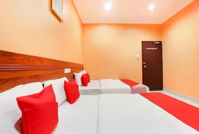 two beds in a room with red and white pillows at Bercam Times Inn Hotel in Ipoh
