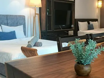 a hotel room with two beds and a table and a tv at Family Suites at Mansion One by MAJ in George Town