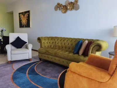 a living room with a green couch and a chair at Tree Family Executive Suite 3 BR /8 PAX Gurney in Tanjong Tokong