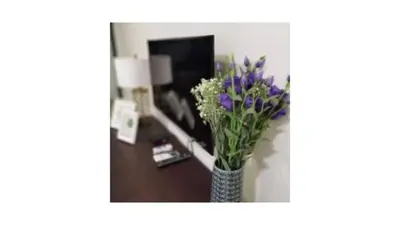 a vase with purple flowers in a room at Tree Family Executive Suite 3 BR /8 PAX Gurney in Tanjong Tokong