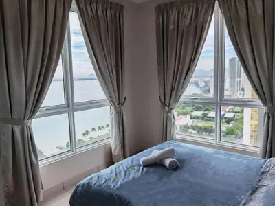 a bedroom with windows and a bed with a towel on it at SUMMERSET 8PAX 3BR LUXURY SEAVIEW SUITE ROOM in George Town