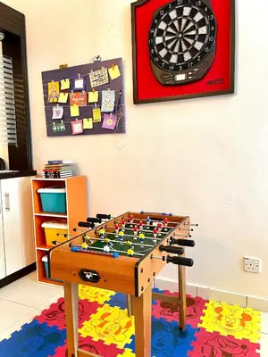 a table with a dart board on a wall at Zarahome in Tambun