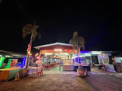 a gas station with tables and chairs at night at Yussal Homestay in Simpang Ampat Semanggol