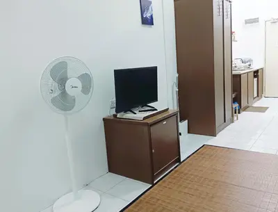 a room with a television and a fan on a cabinet at Yussal Homestay in Simpang Ampat Semanggol