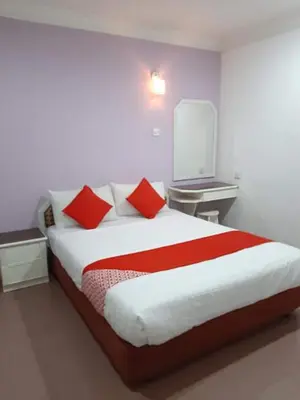 a bedroom with a bed with two red pillows at G CITY HOTEL in Teluk Intan