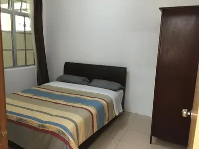 a small bedroom with a bed with a striped blanket at Cameron Pasar Malam Apartment @ Crown Imperial Court in Cameron Highlands