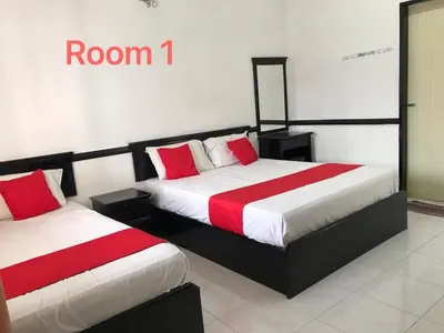 two beds with red and white sheets in a room at 66 Semi-D Homestay in Teluk Intan