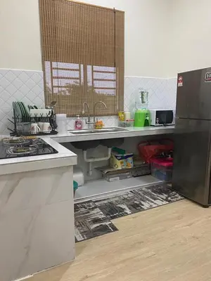 an empty kitchen with a refrigerator and a counter at Ainaz Homestay Balik Pulau in Balik Pulau