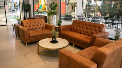 a lobby with brown leather couches and a table at Hotel Brynton at Cameron Centrum Mall in Cameron Highlands