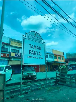 a sign in front of a parking lot with cars at Rumah Singgah in Pantai Remis
