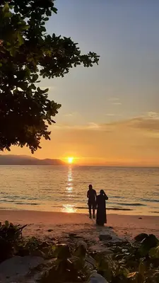 two people walking on the beach at sunset at Woodsbury Suites IKEA House Butterworth Penang in Butterworth