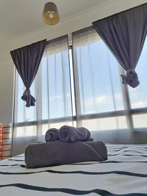 a bed with two towels on it with windows at Woodsbury Suites IKEA House Butterworth Penang in Butterworth
