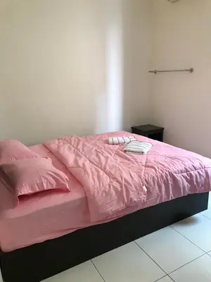 a bed with a pink comforter and pillows on it at Intanova Hotel in Teluk Intan