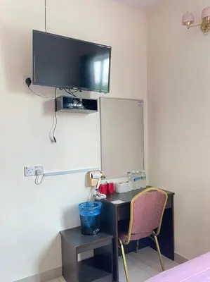 a room with a desk and a tv on the wall at Intanova Hotel in Teluk Intan