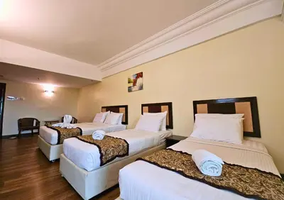 a hotel room with three beds with white sheets at Hotel Taiping Perdana in Taiping