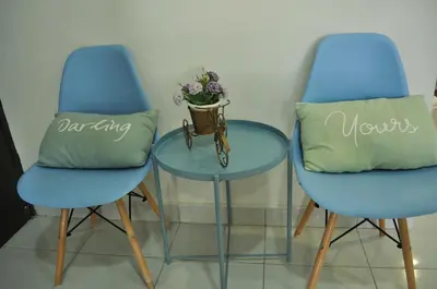 two blue chairs and a glass table with a pillow at De’ Nuhir Homestay Teluk Senangin in Kampong Batu Tiga