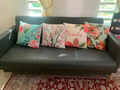 a black couch with pillows on it in a living room at Damai Homestay in Kampong Jabi