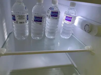 four bottles of water sitting on a shelf in a refrigerator at Damai Homestay in Kampong Jabi