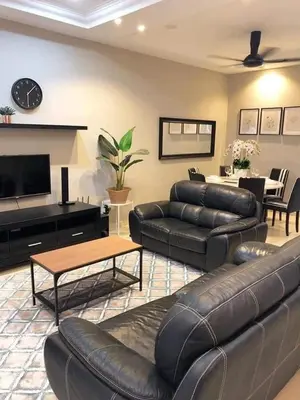 a living room with a leather couch and a table at SB PRIMA VILLA APRTMENT in Tanah Rata