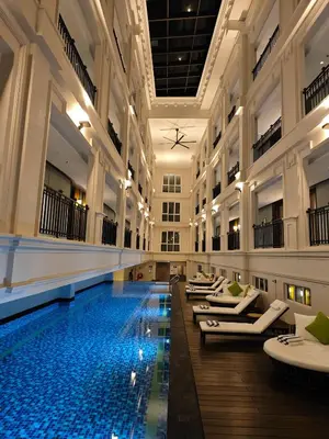 a pool in a building with chaise lounges at The George Penang by The Crest Collection in George Town
