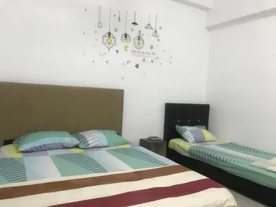 a bedroom with two beds and a clock on the wall at Venus Hollywood Homestay Sitiawan in Seri Manjung