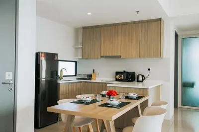 a kitchen with a wooden table and a black refrigerator at The Pine, 3BR Seaview by WStay @ Tropicana 218 Macalister in George Town