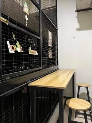 a bird cage with a wooden table and two stools at Batu Feringgi Homestay in Batu Ferringhi