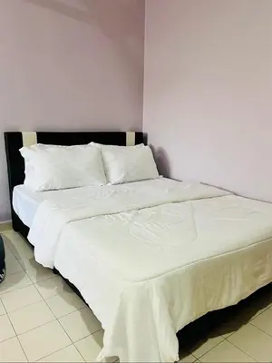a bed with white sheets and pillows in a room at Batu Feringgi Homestay in Batu Ferringhi