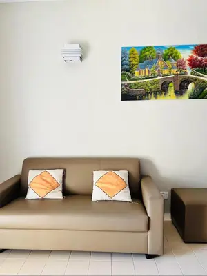 a couch in a living room with a painting on the wall at Batu Feringgi Homestay in Batu Ferringhi