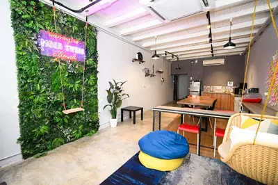 a room with a green wall with a table and chairs at Swing & Pillows @ Beach Street in George Town