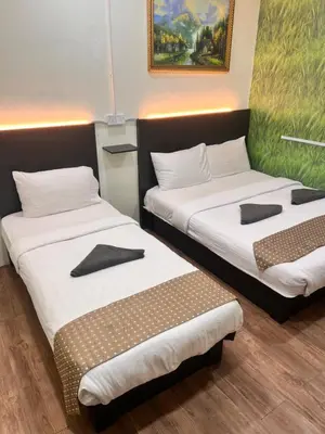 a room with two beds and a painting on the wall at Hotel Citra in Brinchang