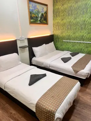 two beds in a room with a painting on the wall at Hotel Citra in Brinchang