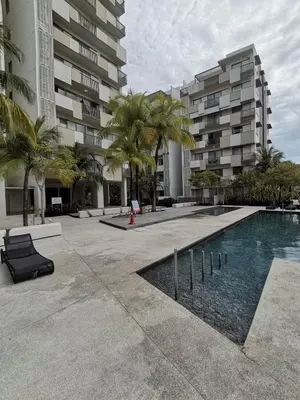 a swimming pool with palm trees in front of a building at By The Sea Batu Ferringhi Beach Front, Seaview And Pool Front in Batu Ferringhi
