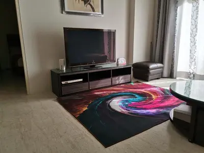 a living room with a tv and a colorful carpet at By The Sea Batu Ferringhi Beach Front, Seaview And Pool Front in Batu Ferringhi