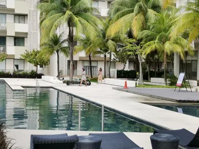 a person walking by a swimming pool with palm trees at By The Sea Batu Ferringhi Beach Front, Seaview And Pool Front in Batu Ferringhi