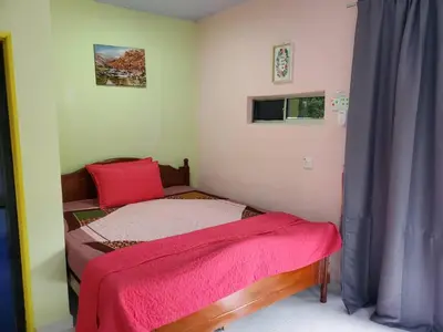 a small bedroom with a bed with a red blanket on it at Inap Desa 3 in Kampong Siput