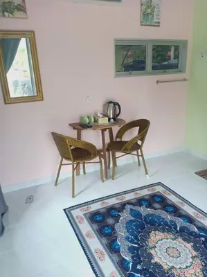 a dining room with a table and chairs and a rug at Inap Desa 3 in Kampong Siput