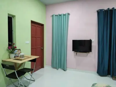 a room with a desk and a television and blue curtains at Inap Desa 1 in Kampong Siput