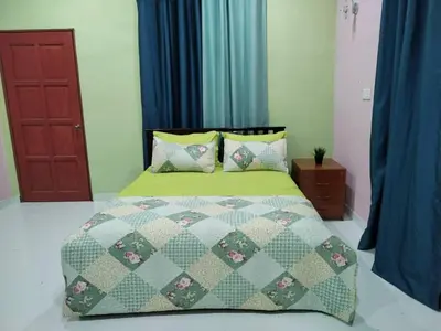 a bed with a green comforter and pillows in a bedroom at Inap Desa 1 in Kampong Siput